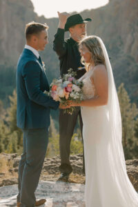 Couple exchanging vows with mountain peaks in the distance.