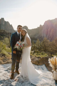 Couple smiling and holding bouquet at Smith Rock ceremony.