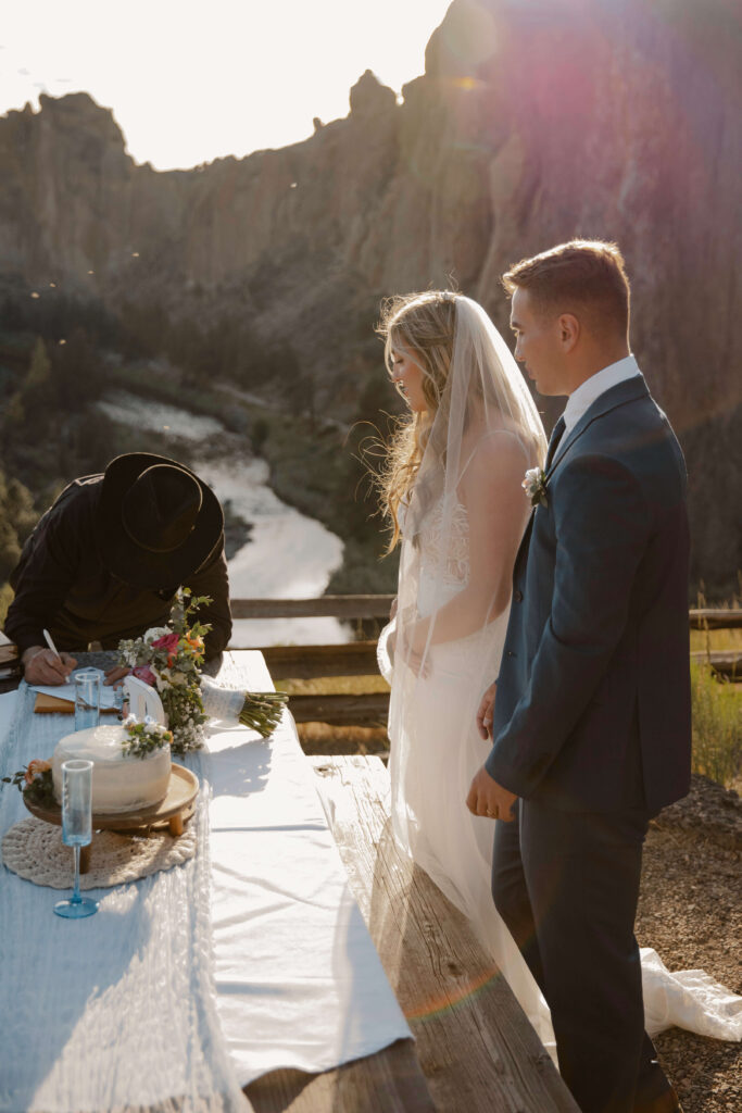 Bride and Groom sign Marriage Certificate with rock formations view behind them