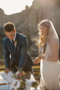Bride and Groom sign Marriage Certificate with rock formations view behind them