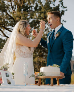 Wedding couple feeds each other cake pieces at smith rock state park