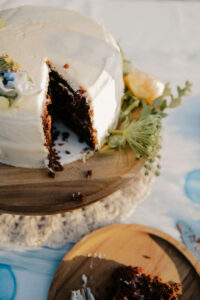 Close up of wedding cake, chocolate with vanilla frosting and flower garnishing on wooden plates