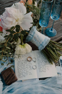 Bridal bouquet with pastel blooms arranged next to vow books and rings at Smith Rock State Park