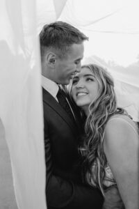 Groom embracing bride under her veil at Smith Rock State Park.