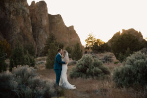 Bride and groom walking together through grassy terrain at Smith Rock State Park.