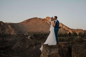 Bride and groom standing together on a cliff edge at Smith Rock.