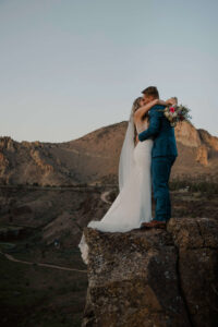 Bride and groom standing together on a cliff edge at Smith Rock.