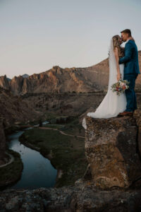 Bride and groom standing together on a cliff edge at Smith Rock.