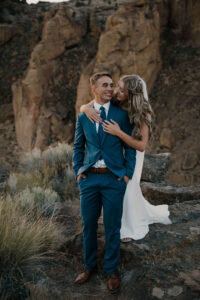 Couple embracing on an overlook with Smith Rock formations in the background.