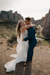 Groom lifts bride during an embrace at canyon overlook.