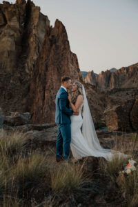 Bride and groom laughing together on a rocky cliff at Smith Rock State Park.