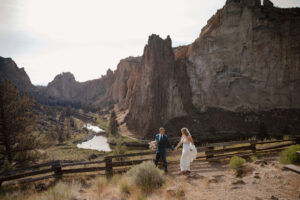 Bride and groom walk hand in hand along Smith Rock trail.