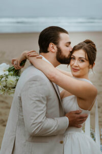 Couple exchanges a kiss on the oregon coast at their vow renewal