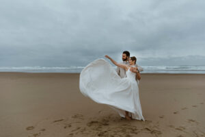 Bride throws the train of her dress for a dramatic beach wedding picture
