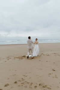 Couple runs on the beach at their oregon coast vow renewal