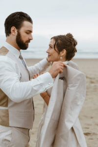 Groom puts a jacket on his bride at their oregon coast vow renewal