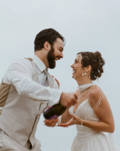 Couple pops a bottle of champagne at their oregon coast vow renewal
