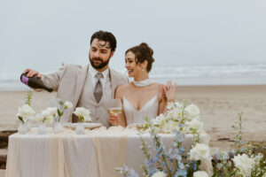 Couple pops a bottle of champagne at their oregon coast vow renewal