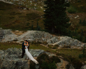couple kisses while standing on a rock at mount rainier