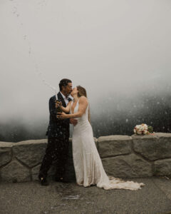 couple pops a champagne bottle after eloping at mount rainier